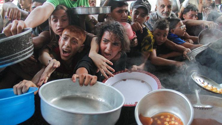 FILE PHOTO: Palestinians gather to receive food cooked by a charity kitchen, amid the Israel-Hamas conflict, in the northern Gaza Strip