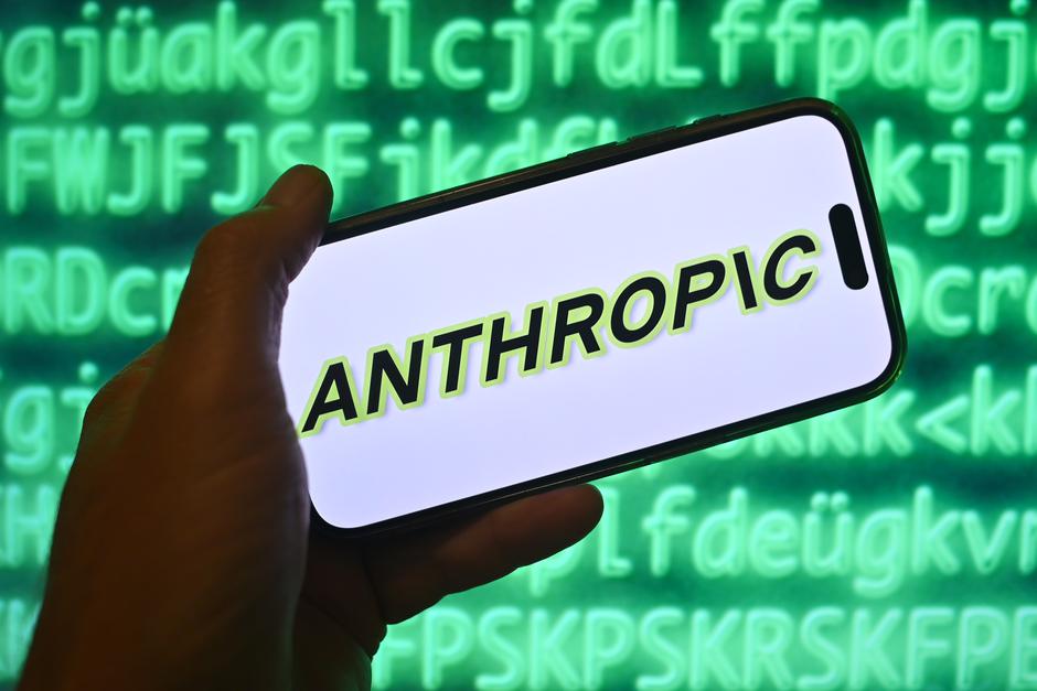 Hand shows a smartphone with the Anthropic logo in front of a computer background | Author: Frank Hoermann / SVEN SIMON
