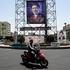 People ride past a banner with a picture of Iran's Supreme Leader, Mojtaba Khamenei, in Tehran