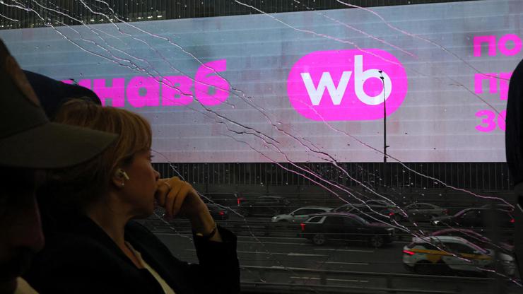 A woman rides a train past a screen advertising the Wildberries online retailer in Moscow