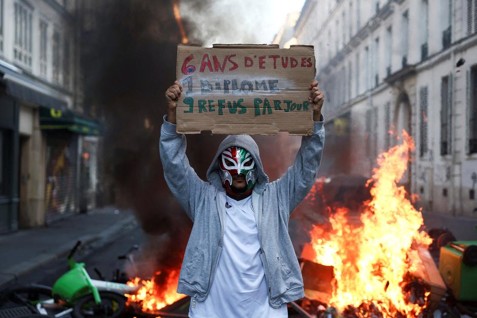 A person wearing a mask holds a placard, the day after a national day of demonstrations against the cost of living and rising fuel prices, in Paris | Author: Abdul Saboor