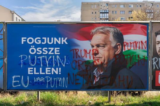 Defaced Fidesz billboard with anti-war slogan and graffiti referencing Putin and Trump in Budapest during Hungary’s 2026 election campaign.