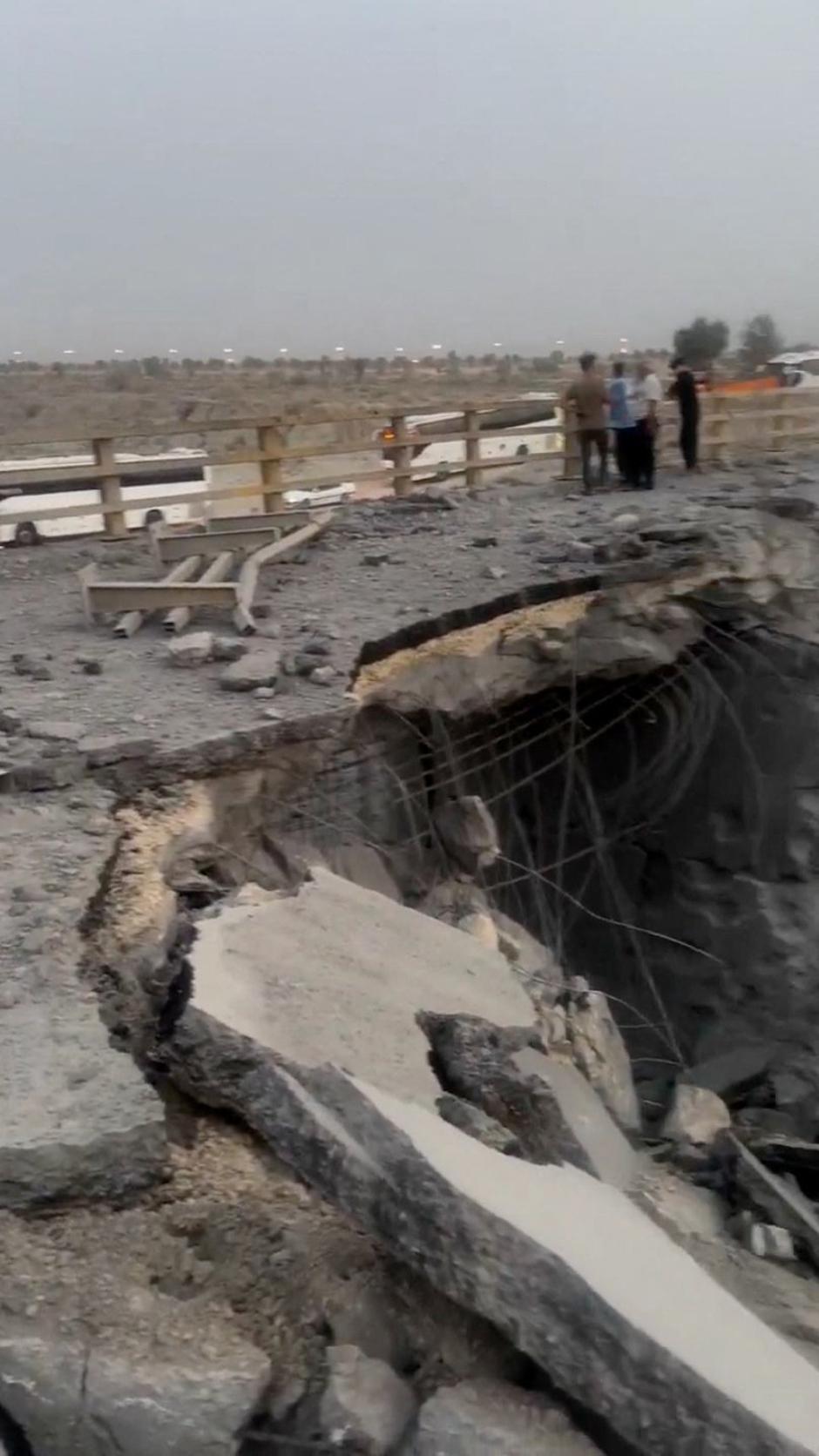People stand near a damaged portion of a bridge in the aftermath of a strike, in Bandar Khamir | Author: Social Media