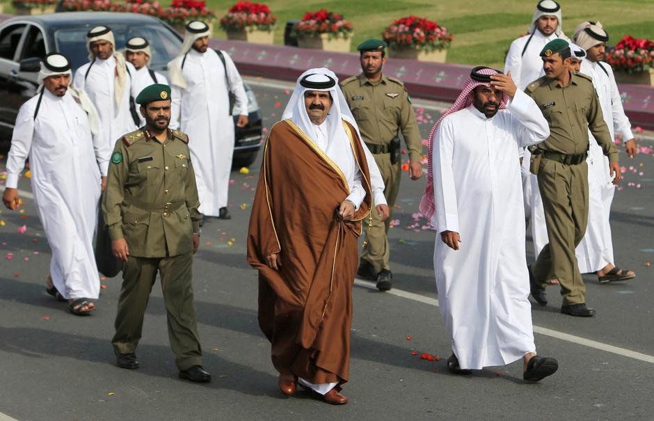 FILE PHOTO: Qatar's Emir Sheikh Hamad bin Khalifa al-Thani (C) walks beside members of a security team as he arrives to attend National Day celebrations in Doha | Author: FADI AL-ASSAAD/REUTERS