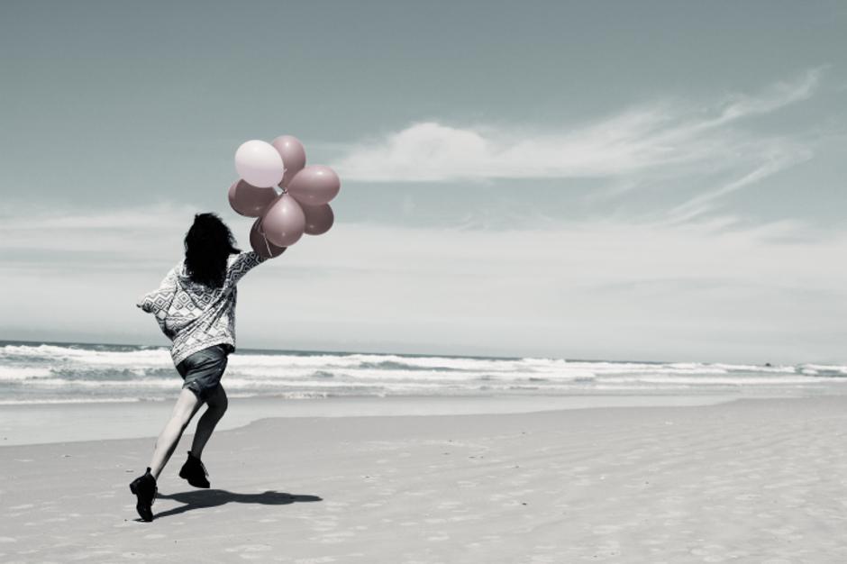 Žena trči na plaži s balonima | Author: Thinkstock