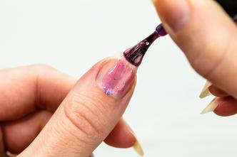 Female hands doing manicure, nail polish in gold glitter color on a white background. Skin and nail care salon concept