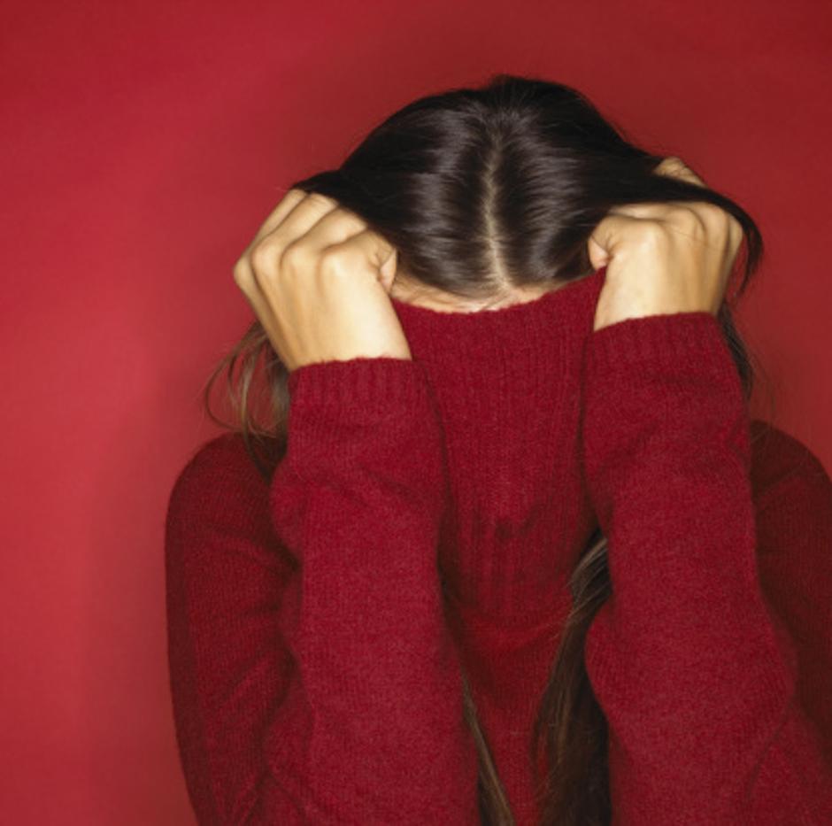 Preplašena žena s navučenim puloverom preko glave | Author: Thinkstock