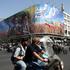 People ride past a billboard depicting the late leader of the Islamic Revolution, Ayatollah Ruhollah Khomeini, and the late Iran's Supreme Leader Ayatollah Ali Khamenei, on a street in Tehran