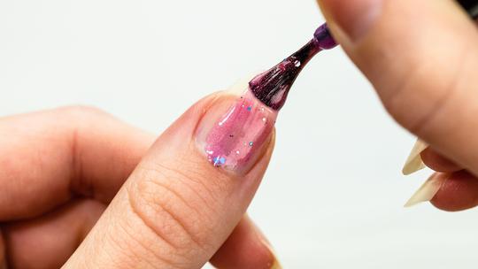 Female hands doing manicure, nail polish in gold glitter color on a white background. Skin and nail care salon concept