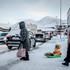A person pulls a child on a snow sled, in Nuuk