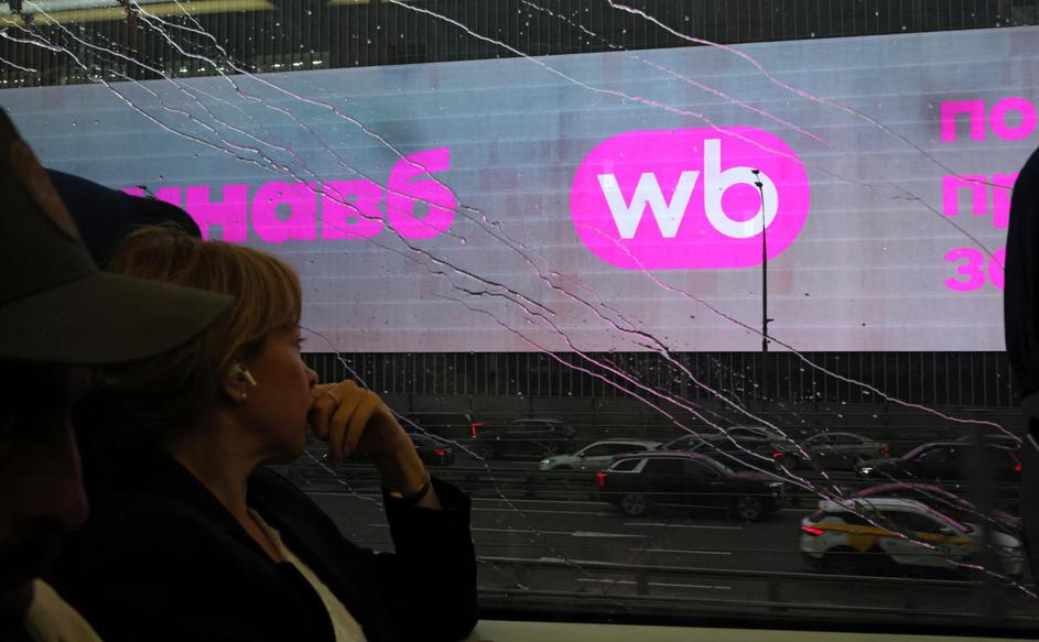 A woman rides a train past a screen advertising the Wildberries online retailer in Moscow