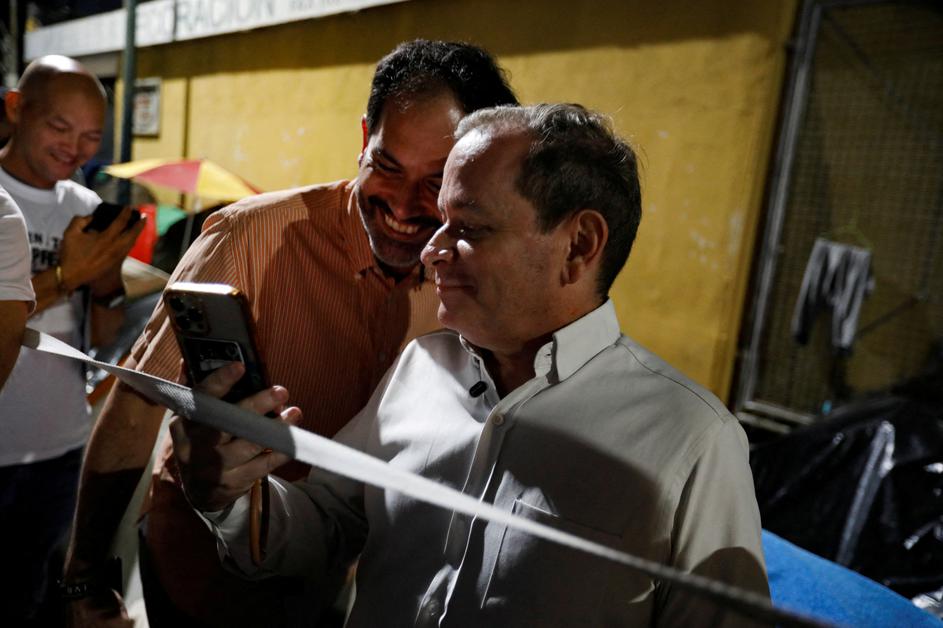 FILE PHOTO: Venezuelan opposition politician Juan Pablo Guanipa talks on a video call through a smartphone outside National Police Zone 7 Detention Centre, in Caracas