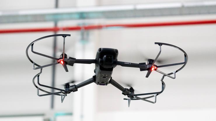 Augsburg, Bavaria, Germany - September 30, 2025: A DJI Mavic 3 drone hovers in flight with LED light on and protective f