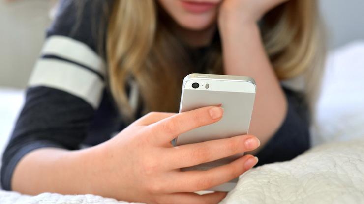 Teen / tween girl holding a mobile phone (iphone)
