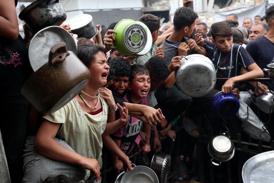 Palestinians receive food cooked by a charity kitchen, in Beit Lahia