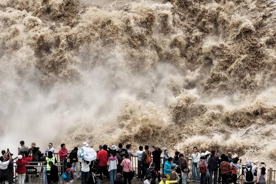 YAN AN, CHINA - SEPTEMBER 20: Tourists visit the Hukou Waterfall on the Yellow River as water volume significantly incre