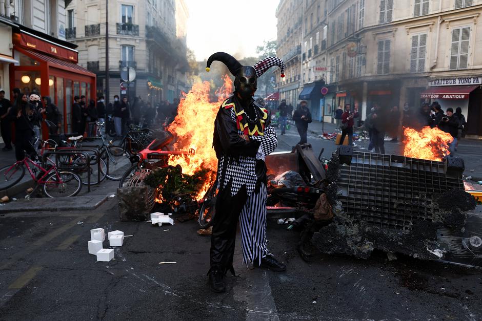 A demonstrator wearing a costume stands in front of burning flames, in Paris | Author: Abdul Saboor