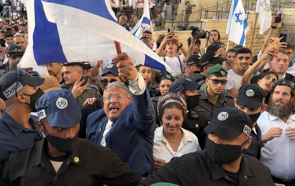 JERUSALEM - MAY 14: Israeli policemen escort Minister of National Security and far-right politician Itamar Ben-Gvir as he is surrounded with ultra-nationalist Israelis outside Damascus Gate during the Jewish nationalist "Flag March" to mark "Jerusalem Day