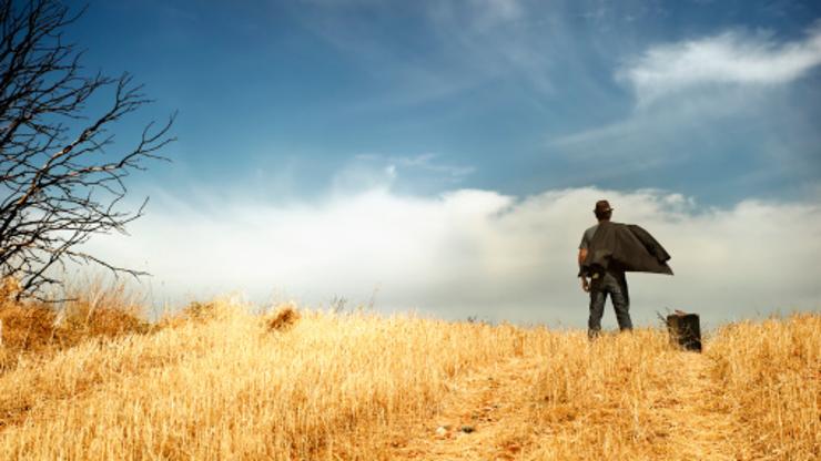 Čovjek stoji usred polja i gleda u daljinu