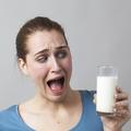 Žena koja sa strahom gleda u čašu mlijeka