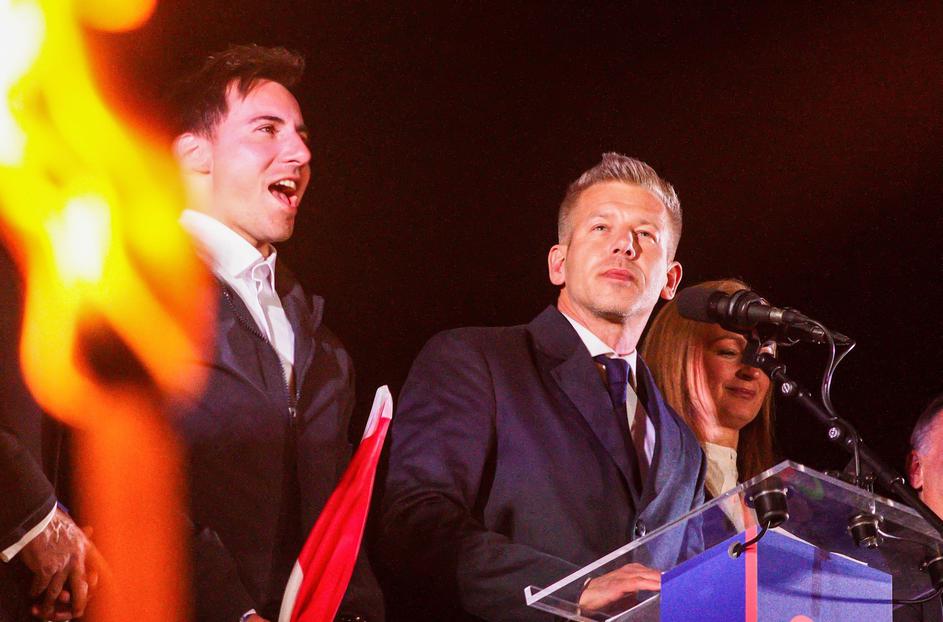 With lit torches flickering in the foreground, new Prime Minister of Hungary Peter Magyar delivers his victory speech. On the evening of April 12th, the day of the Hungarian parliamentary elections, supporters of the Tisza political party gather at Batthy
