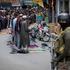Kashmiri muslims offer Friday prayers on a road as a security personnel stands guard in Srinagar
