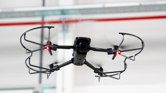 Augsburg, Bavaria, Germany - September 30, 2025: A DJI Mavic 3 drone hovers in flight with LED light on and protective f