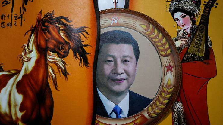A portrait of Chinese President Xi Jinping seen next to traditional paintings in Hohhot