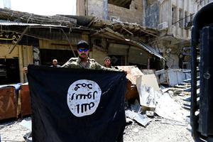 Pripadnik snaga iračke vojske drži u rukama zarobljenu zastavu ISIL-a