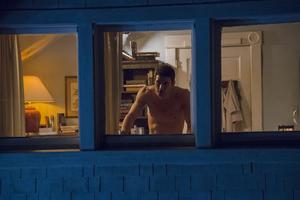 Filmska scena u kojoj muškarac gleda kroz prozor kuće