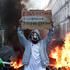 A person wearing a mask holds a placard, the day after a national day of demonstrations against the cost of living and rising fuel prices, in Paris