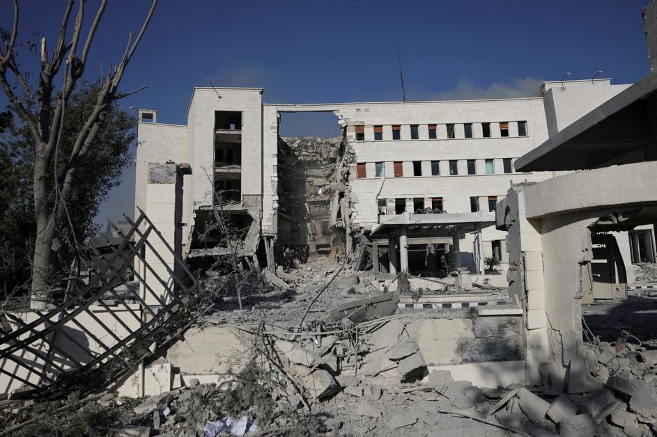 People gather near a damaged site, in Damascus