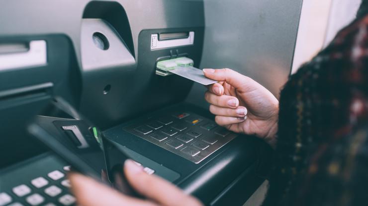 Hand of young woman inserting credit card into cash machine