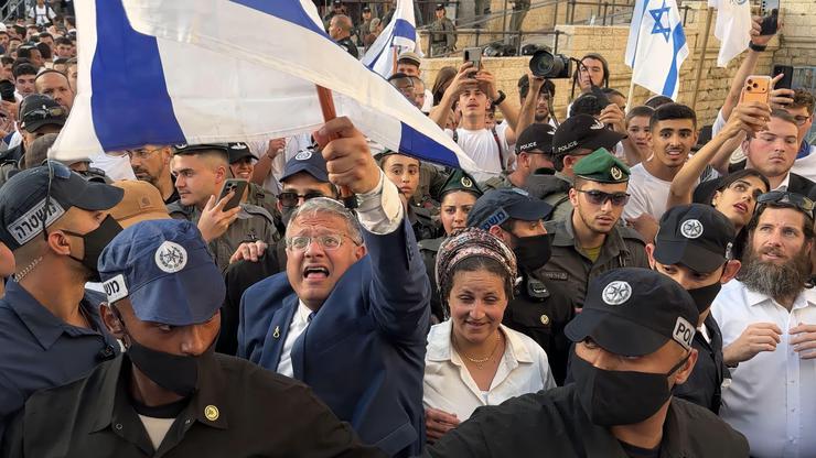 JERUSALEM - MAY 14: Israeli policemen escort Minister of National Security and far-right politician Itamar Ben-Gvir as he is surrounded with ultra-nationalist Israelis outside Damascus Gate during the Jewish nationalist "Flag March" to mark "Jerusalem Day