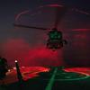 Undisclosed Location, United States. 18 March, 2026. A U.S. Navy sailor signals a MH-60S Sea Hawk helicopter, attached to the Chargers of Helicopter Sea Combat Squadron 14, to take off during night operations on the deck of the Arleigh Burke-class guided-