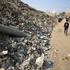 Palestinians walk past the remains of a munition, during a ceasefire between Israel and Hamas, in Gaza City