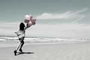 Žena trči na plaži s balonima