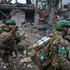 Ukrainian servicemen walk past a damaged apartment building  in the frontline town of Druzhkivka