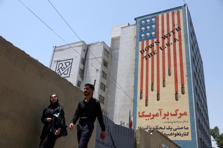 People walk near an anti-U.S. mural in Tehran