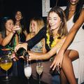A lively group of young women enjoying a night out at a night club, sharing laughter and pouring champagne.