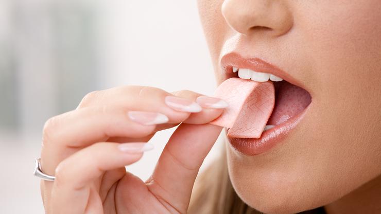 Žena koja stavlja žvakaću gumu u usta