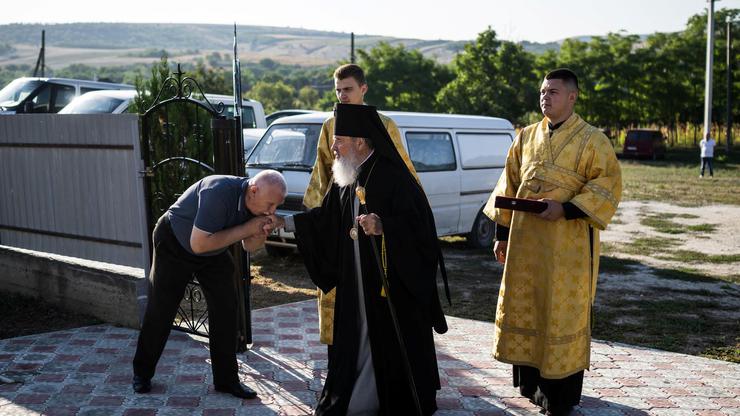 A man kisses Archbishop Marchel's hand as he arrives for his Mass at a church in Slobozia-Magura
