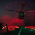 Undisclosed Location, United States. 18 March, 2026. A U.S. Navy sailor signals a MH-60S Sea Hawk helicopter, attached to the Chargers of Helicopter Sea Combat Squadron 14, to take off during night operations on the deck of the Arleigh Burke-class guided-