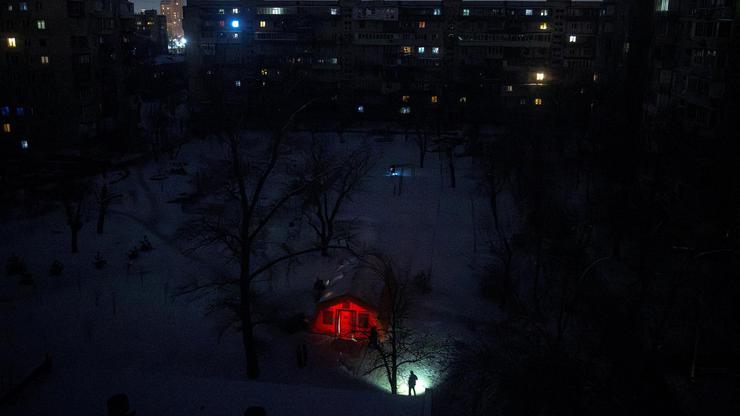 A person carrying a torch approaches a tent provided by emergency services for residents whose apartments are left without heating during sub-zero temperatures in Kyiv
