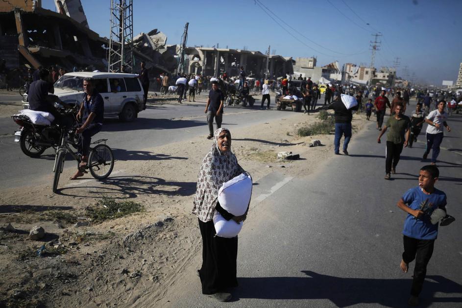 Displaced Palestinians ferry bags of food aid after people stormed a World Food Programme warehouse in Deir el-Balah in the central Gaza Strip
