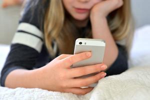 Teen / tween girl holding a mobile phone (iphone)