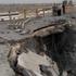 People stand near a damaged portion of a bridge in the aftermath of a strike, in Bandar Khamir