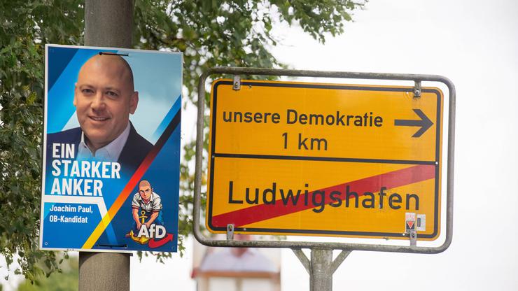 (Fotomontage) Plakat des ausgeschlossenen Ludwigshafener Bürgermeisterkandidaten Joachim Paul (AfD), daneben ein Ortsaus