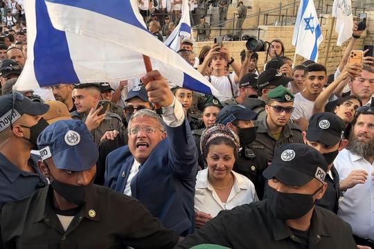 JERUSALEM - MAY 14: Israeli policemen escort Minister of National Security and far-right politician Itamar Ben-Gvir as he is surrounded with ultra-nationalist Israelis outside Damascus Gate during the Jewish nationalist "Flag March" to mark "Jerusalem Day