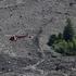 A helicopter flies over debris and dust from a crumbling glacier that partially collapsed and tumbled onto the village of Blatten